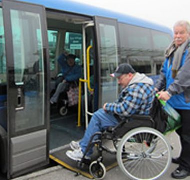 Buddies on the bus Picture of man helping man in wheelchair onto the bus