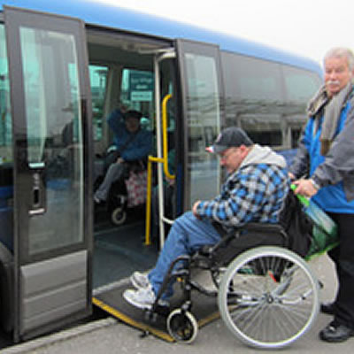 Buddies on the bus Picture of man helping man in wheelchair onto the bus