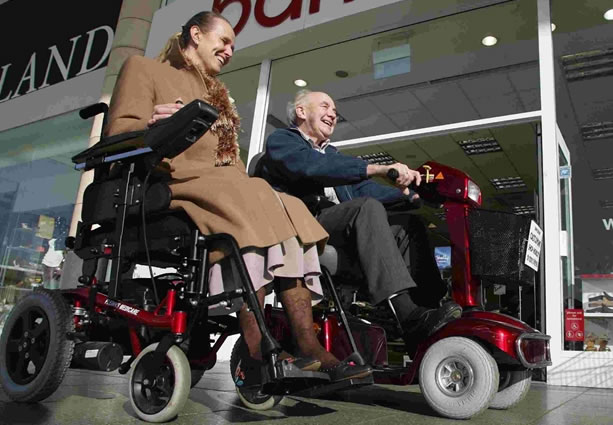 Two people on scooters outside of a shop at Castlepoint